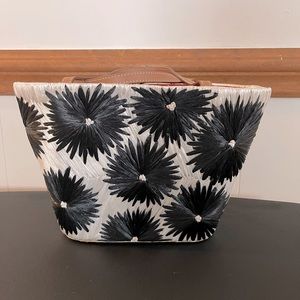 Women’s Kate Spade White straw purse with black straw sunburst flowers.